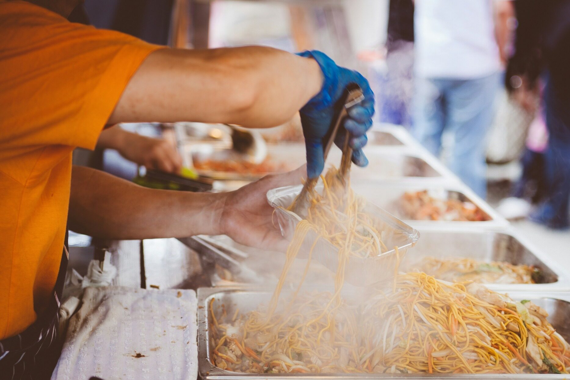 Steaming hot noodles being placed in a to go container
